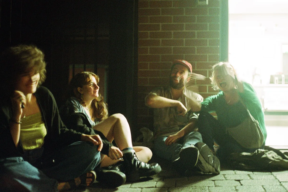 Four people sitting together on front steps in evening light