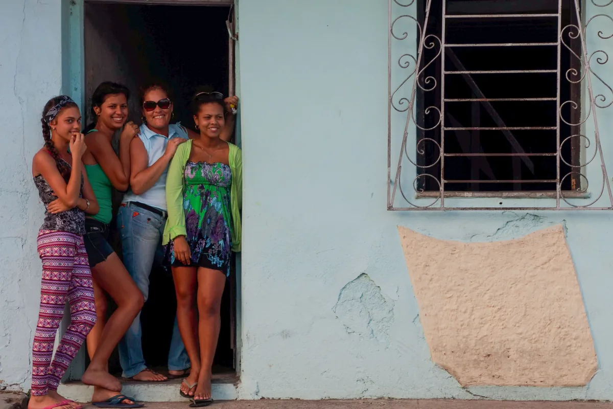 Four women standing together in a doorway on a neighborhood street