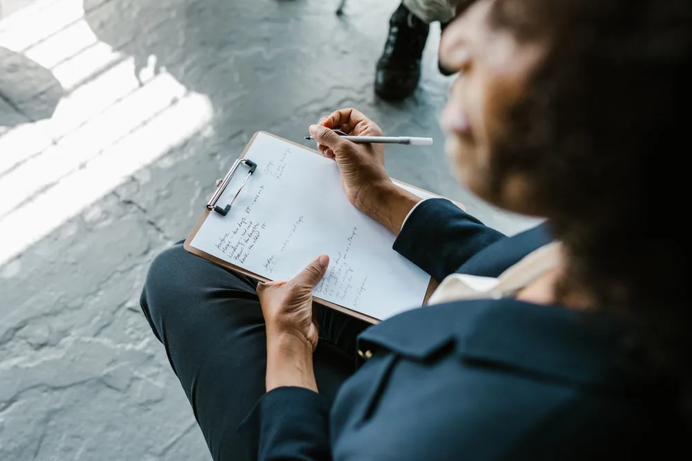 A clinician writing notes on a clipboard during an assessment